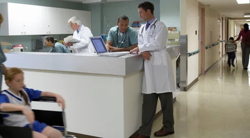 Doctors and patient on wheelchair in hospital corridor