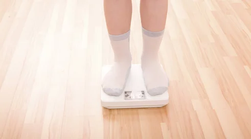 Boy measures weight on floor scales