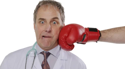 Doctor being punched by a person wearing boxing gloves isolated